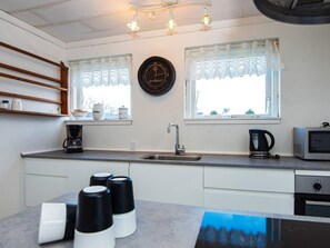 A kitchen with a sink, stove, microwave, and a clock on the wall.