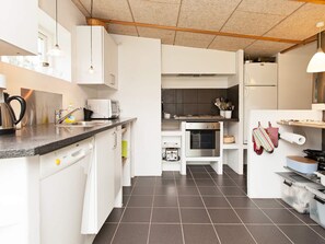 A modern kitchen with white cabinets, a stainless steel range, and a built-in oven.