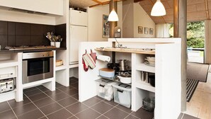 A modern kitchen with a built-in oven, a refrigerator, and a wooden countertop.
