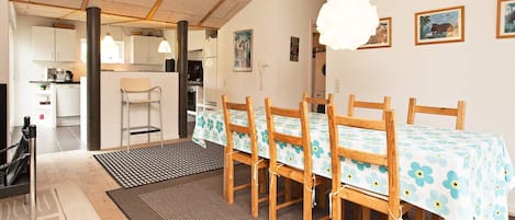 A dining area with a table set for four, wooden chairs, a patterned tablecloth, and a hanging light fixture.