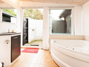 A modern bathroom with a bathtub, a sink, and a toilet. There is a red mat with the word "LOVE" on it at the entrance. - 6 Person Holiday Home in Dronningmolle-by Traum (Dronningmolle)