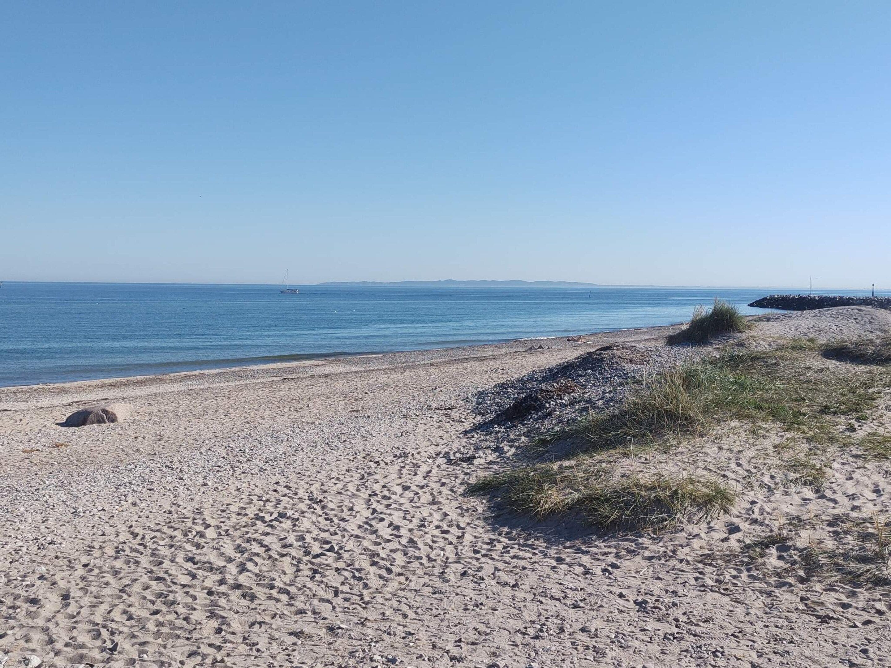 A pebbly beach with a clear sky and calm sea.