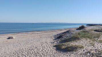 A pebbly beach with a clear sky and calm sea.