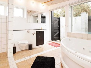 A modern bathroom with a toilet, sink, and bathtub, featuring a black door and a red mat. - 6 Person Holiday Home in Dronningmolle-by Traum (Dronningmolle)