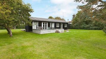 A single-story house with a covered porch, a small deck, and a well-maintained lawn.