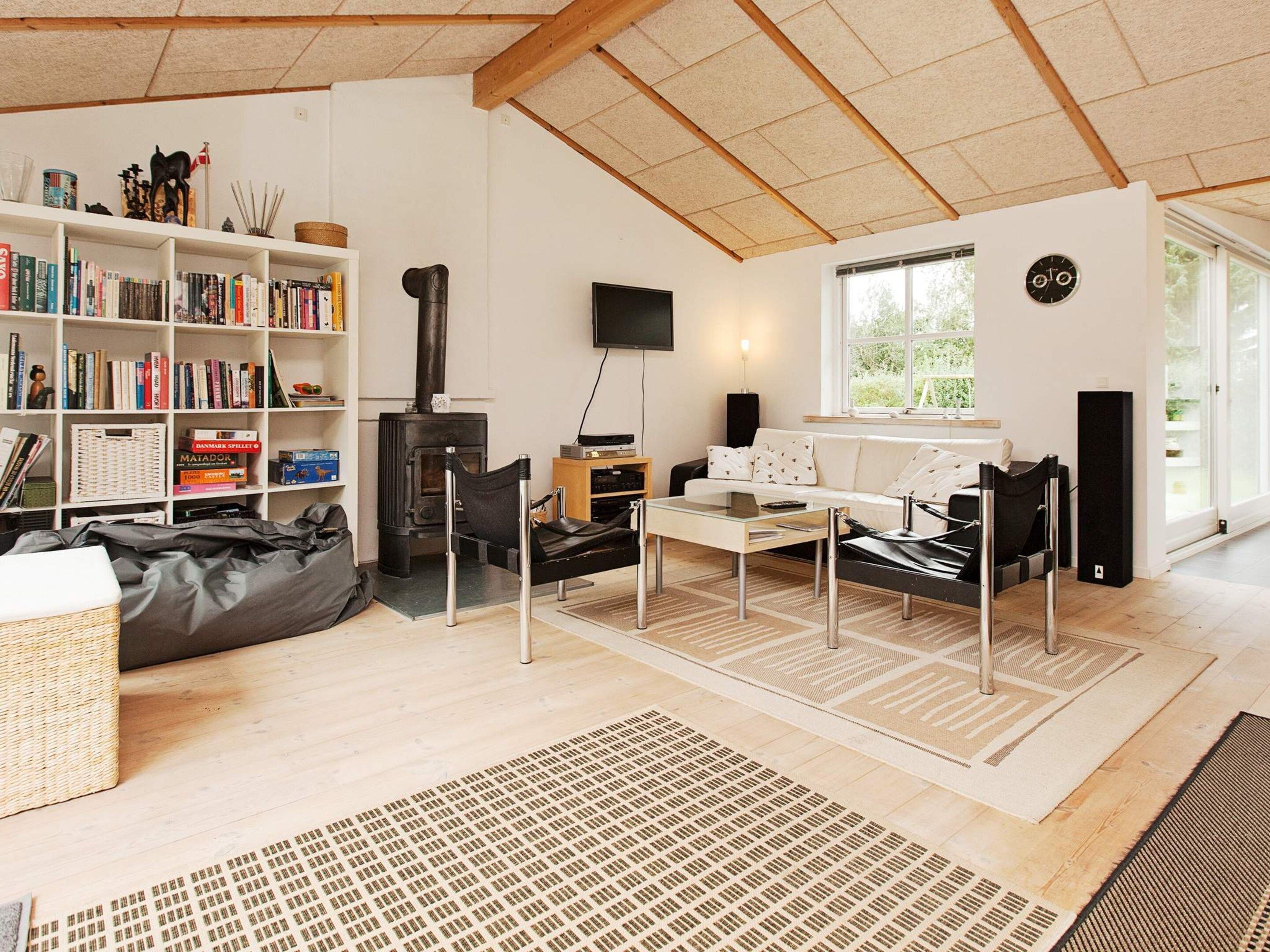 A modern living room with a fireplace, bookshelves, a sofa, and a television.