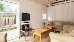 Ein gemütliches Wohnzimmer mit Holzboden, einer Couch, einem Couchtisch und einem Fernseher auf einem Schrank.
