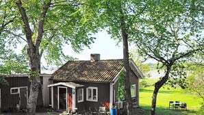 A rustic house with a sloped roof, a front porch, and a small outdoor seating area.