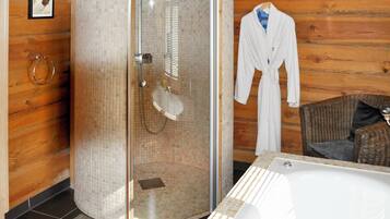 A modern bathroom with a glass-enclosed shower, a bathtub, and a wicker chair.