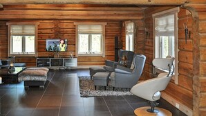 A log cabin interior with a modern living room, a fireplace, and a television.