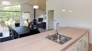 Una cocina moderna con una isla grande, pileta de acero inoxidable y lámparas colgantes.