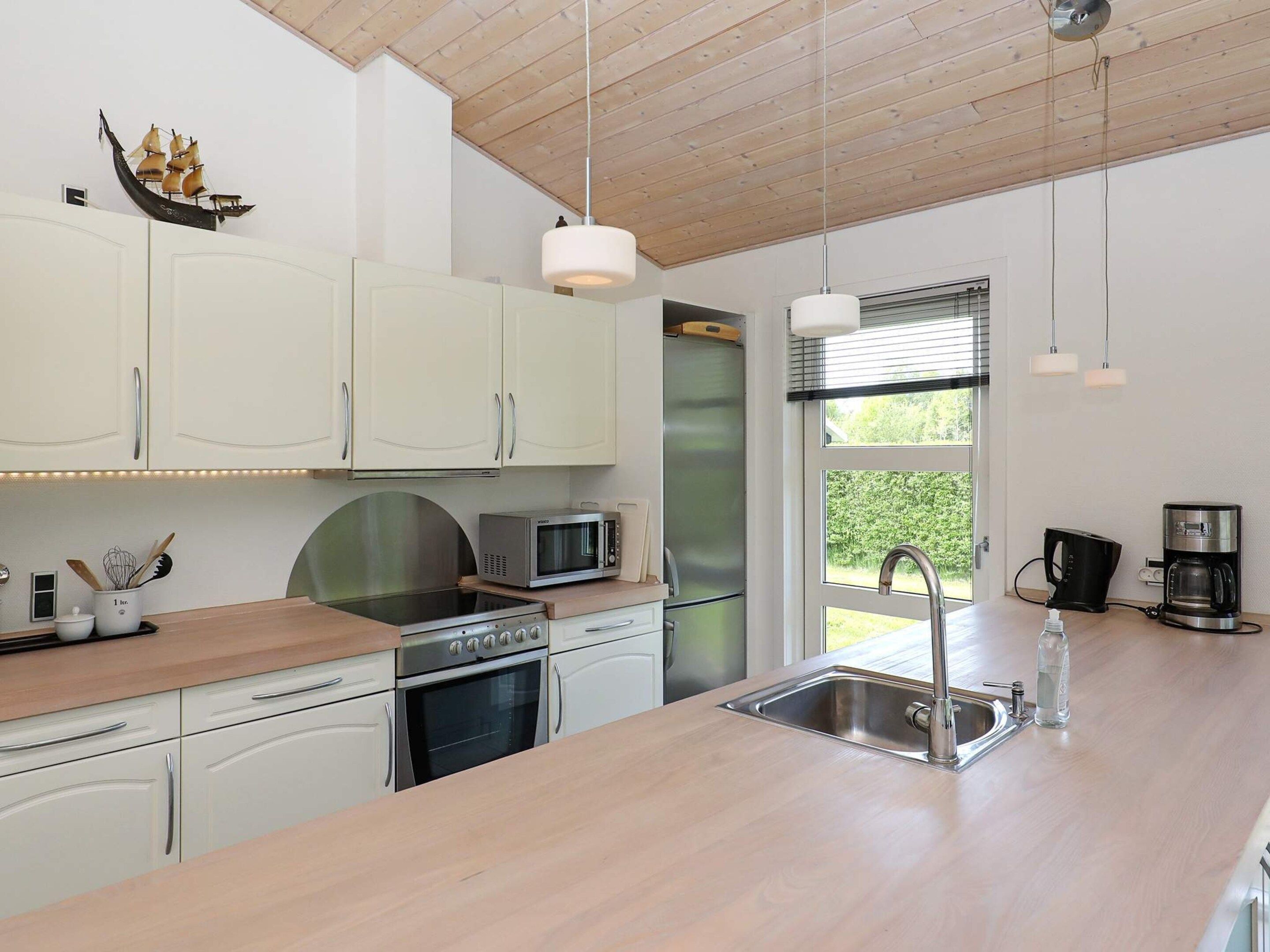 A modern kitchen with white cabinets, stainless steel appliances, and a wooden countertop.