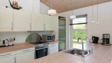 Eine moderne Küche mit weißen Schränken, Edelstahlgeräten und einer Holz Arbeitsplatte.