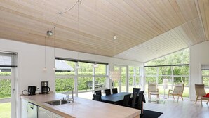 Cocina moderna con una isla grande, armarios blancos y un comedor con mesa y sillas.