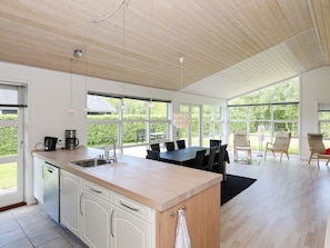 A modern kitchen with a large island, white cabinetry, and a dining area with a table and chairs. - 8 Person Holiday Home in Hals-by Traum (Hals)
