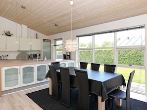 A modern kitchen with white cabinets, a large island, and a dining area with a table and chairs.