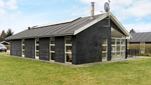 Un edificio negro con techo inclinado, ventanas grandes y una chimenea.