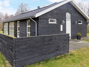A black wooden house with a white door, a small window, and a number '5' on the wall.