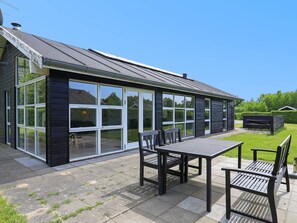 A modern house with a patio area featuring a table and chairs.