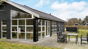 A building with large windows and a patio area with outdoor furniture. - 8 Person Holiday Home in Hals-by Traum (Hals)