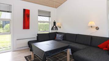 Ein modernes Wohnzimmer mit einem Ecksofa, einem Couchtisch und Blick ins Freie.