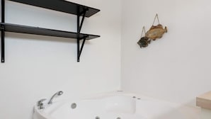 A bathroom with a white bathtub, black metal shelves, and a wall-mounted fish decoration. - 8 Person Holiday Home in Hals-by Traum (Hals)