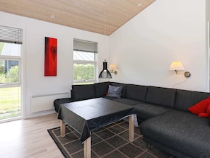 A modern living room with a sectional sofa, a coffee table, a red artwork, and two wall-mounted lamps.