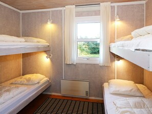 A bedroom with bunk beds, a window with curtains, and a radiator.