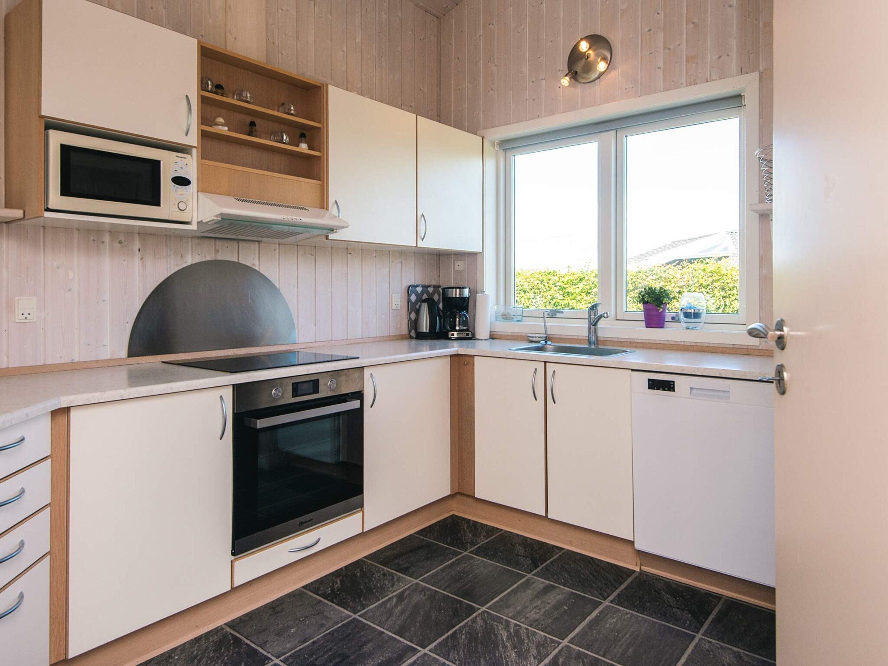Una cocina moderna con horno empotrado, microondas y cafetera.