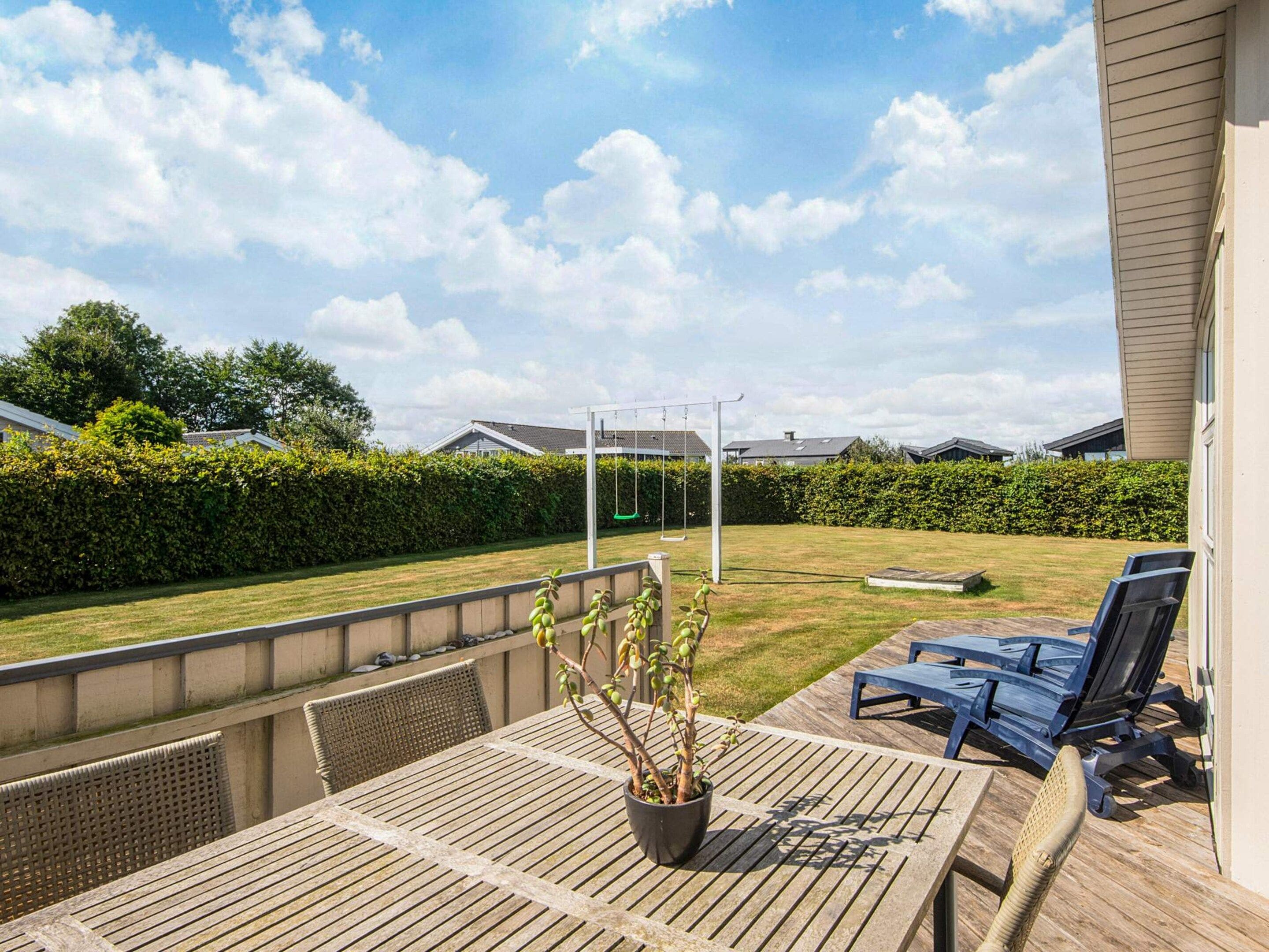 A patio area with a table, chairs, a swing set, and a view of the backyard.