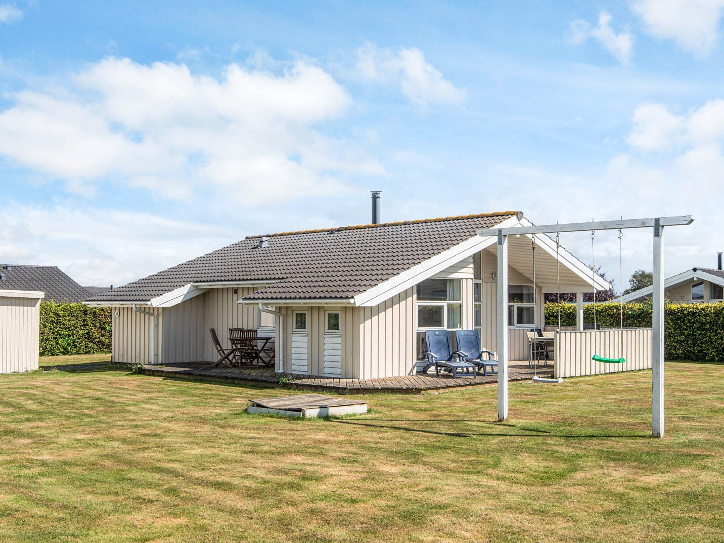 A single-story house with a covered patio, a small deck, and a swing set.