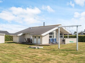 A single-story house with a covered patio, a small deck, and a swing set.
