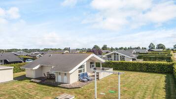 A row of single-story mobile homes with attached porches, a grassy yard, and a swing set.