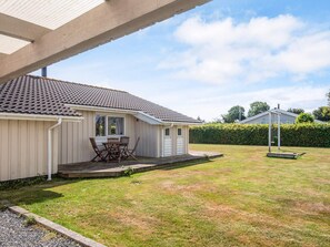 A single-story house with a tiled roof, a small porch with a table and chairs, and a well-maintained lawn. - Pleasing Holiday Home in Haderslev near Sea (Haderslev)