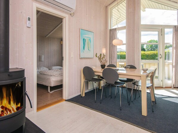 A cozy room with a bed, a dining table with chairs, a fireplace, and a large window with a view.