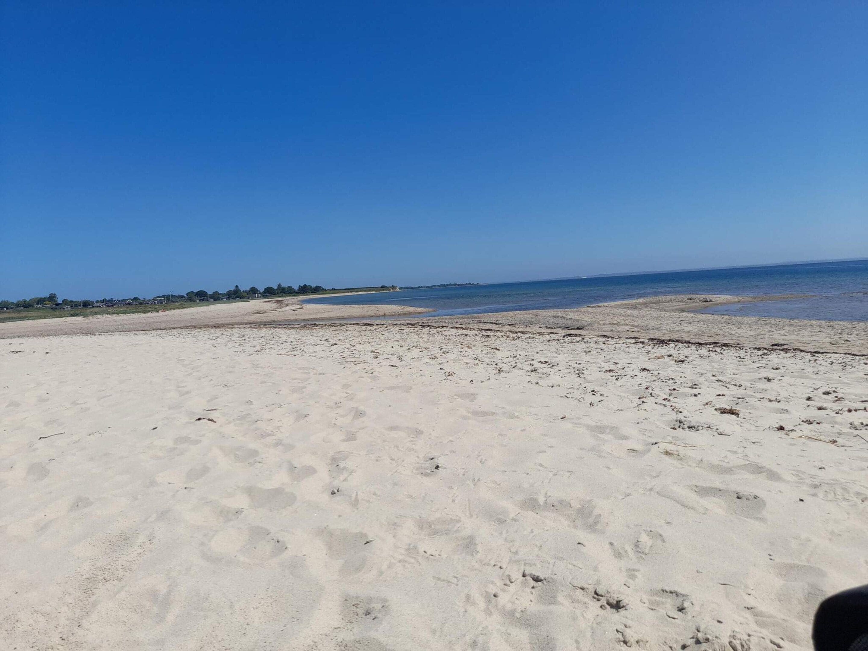 A sandy beach with footprints and a clear blue sky.