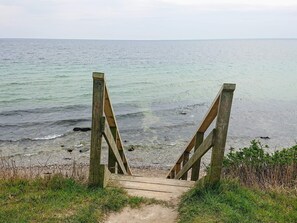 A wooden staircase leading to a beach with a view of the sea.