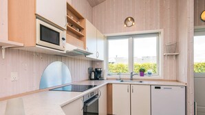 A modern kitchen with a built-in microwave, oven, and dishwasher. There is a window with a view of greenery outside. - Pleasing Holiday Home in Haderslev near Sea (Haderslev)