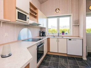A modern kitchen with a built-in microwave, oven, and dishwasher. There is a window with a view of greenery outside. - Pleasing Holiday Home in Haderslev near Sea (Haderslev)