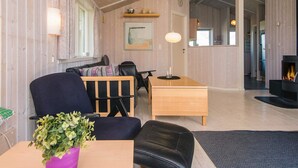 A cozy living room with a wooden ceiling, a dining area with a table and chairs, a fireplace, and a large window. - Pleasing Holiday Home in Haderslev near Sea (Haderslev)