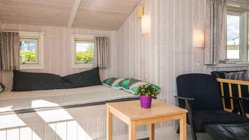 A cozy room with a bed, a wooden table, a chair, and a window with curtains.