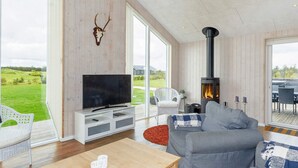 A modern living room with a large TV, a fireplace, and a view of the outdoors.