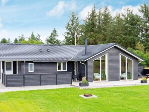 A modern house with a dark exterior, a tiled roof, and a large glass door leading to a covered porch. - 9 Person Holiday Home in Hojslev-by Traum (Hojslev)