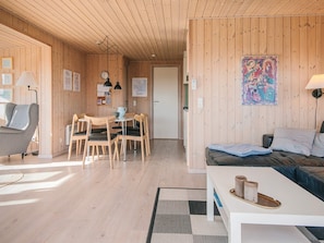 A wooden-paneled room with a dining area, a bed, and a wall-mounted lamp.