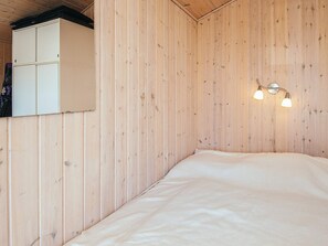 A wooden-paneled room with a bed, a wardrobe, and a wall-mounted light fixture. - Spacious Holiday Home in Hejls near Sea (Hejls)