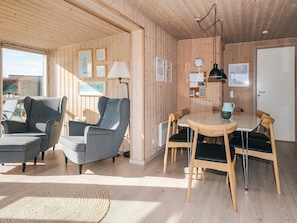 A cozy room with wooden walls, a round table, and two grey armchairs.