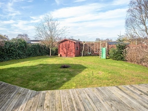 A backyard with a wooden deck, a red shed, a swing set, and a green slide. - Spacious Holiday Home in Hejls near Sea (Hejls)