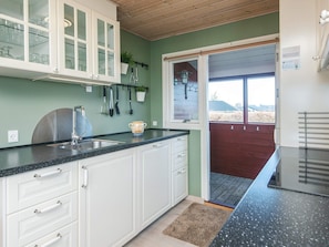 A kitchen with white cabinets, a black countertop, and a window with a view of the outdoors.