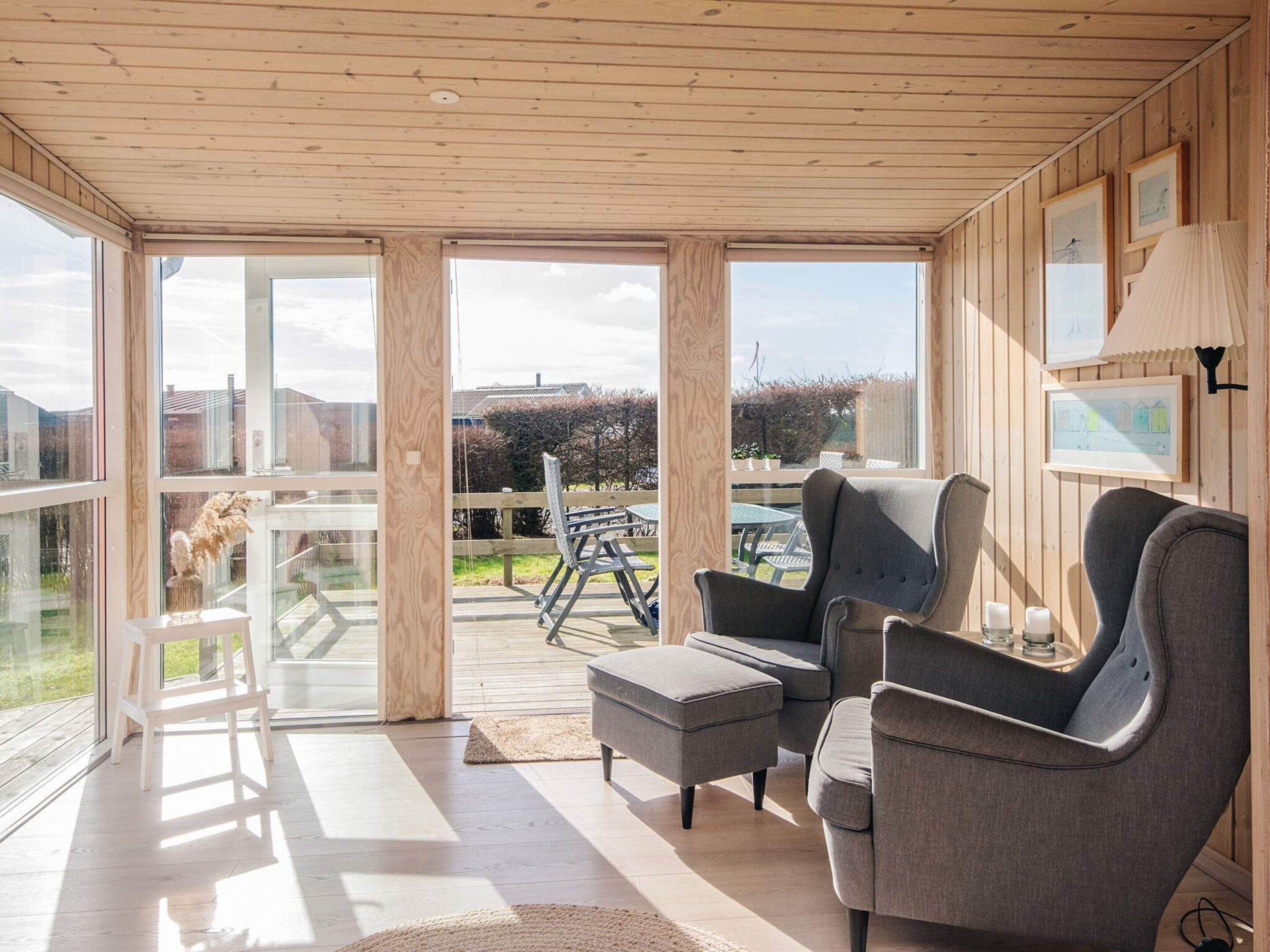 A spacious room with large windows, wooden ceiling, and a view of the outdoors.