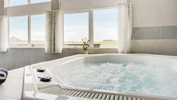 A modern bathroom with a large bathtub, large windows, and a view of the countryside. - 30 Person Holiday Home in Bogense (Bogense)